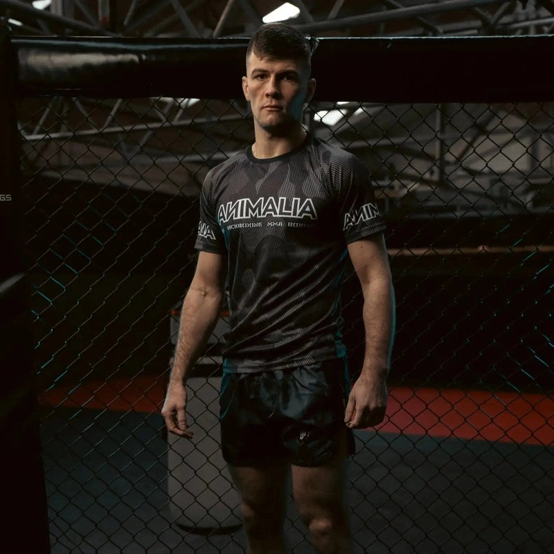 Male model wearing Camo Muay Thai shorts and matching t-shirt in MMA cage