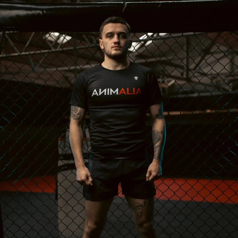 Black unisex polyester Choirboy athletic t-shirt with front logo on male model in gym setting