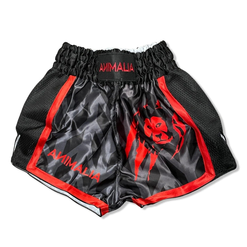Flat lay of black kids Muay Thai shorts with red animal face and satin finish